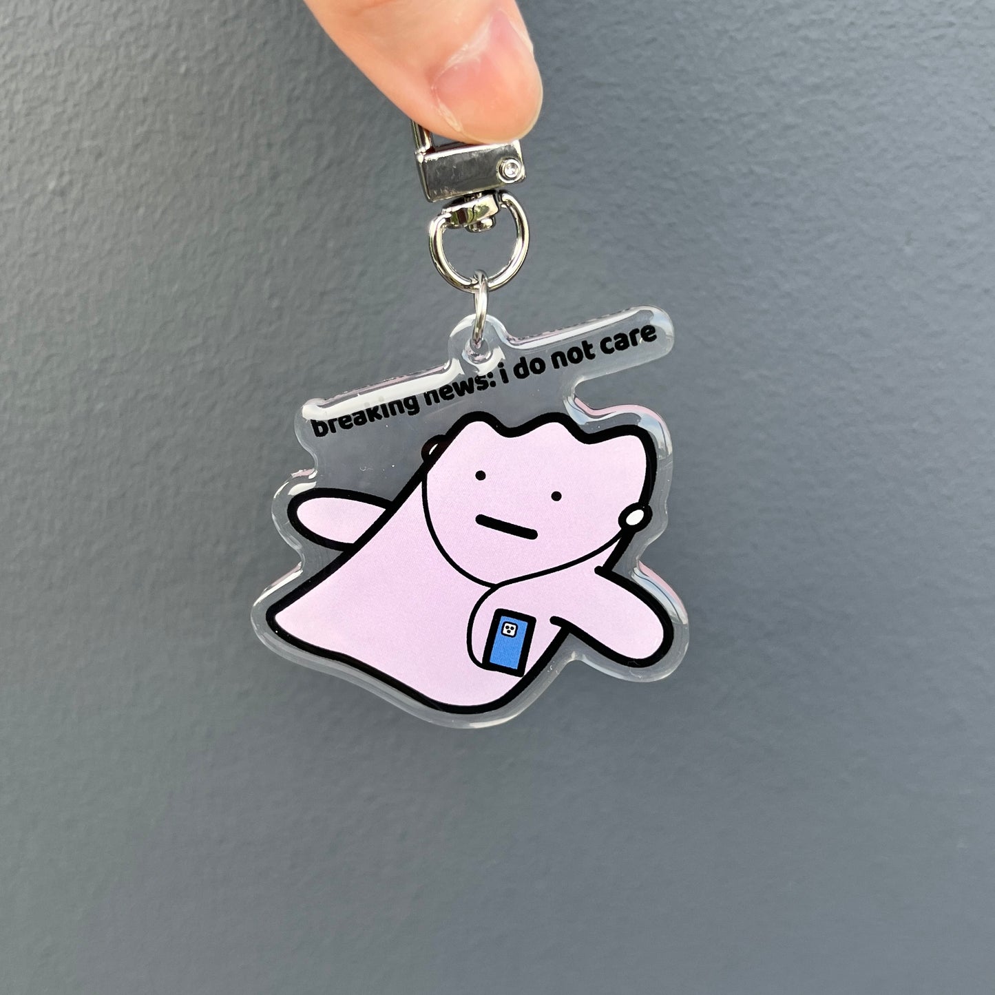 waterproof acrylic keychain with the text “Breaking news: I do not care" on a plain background