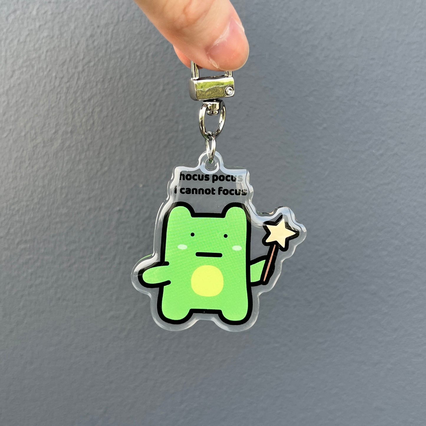 waterproof frog acrylic keychain with the text “Hocus pocus I cannot focus" on a plain background