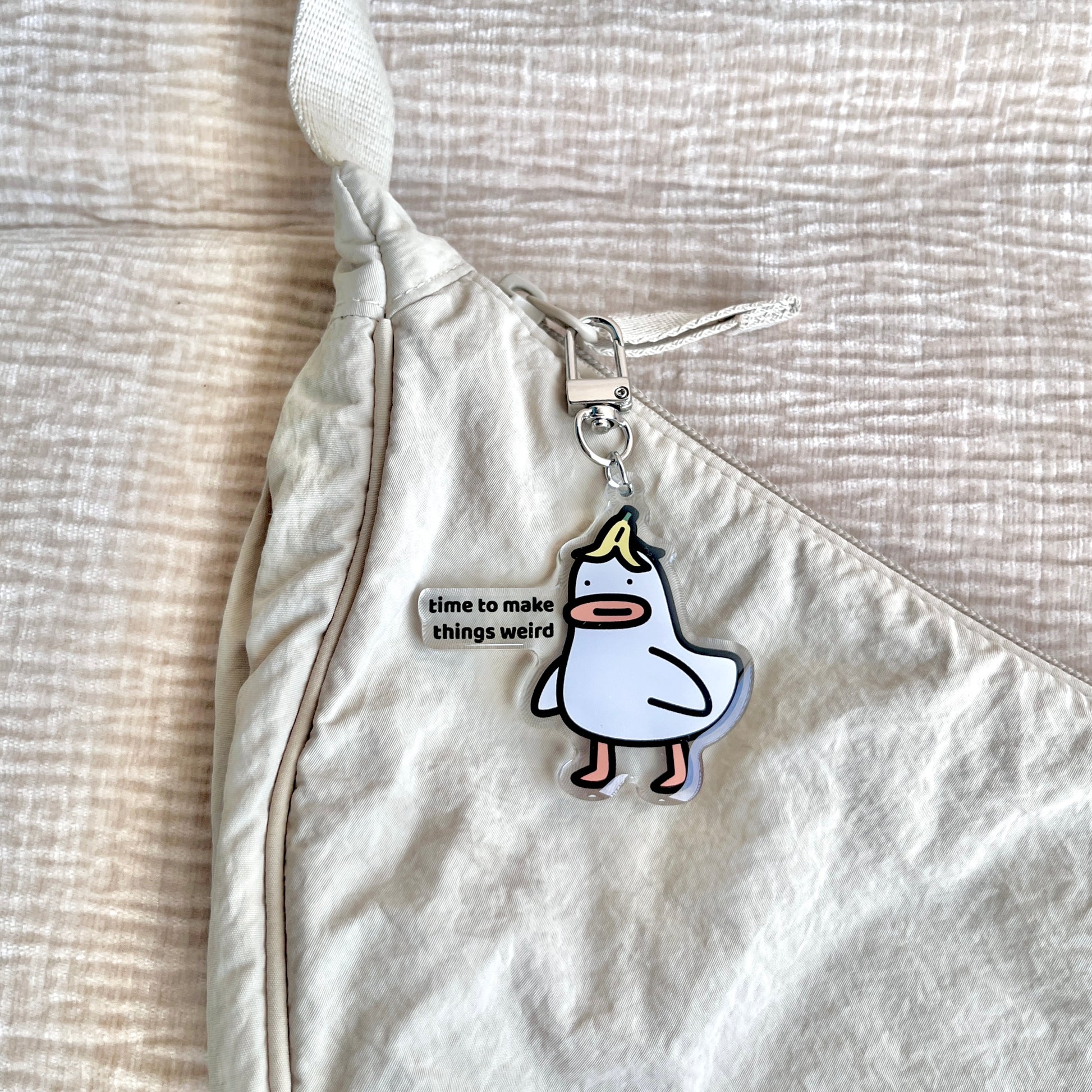 waterproof acrylic goose keychain with the text “Time to make things weird" on a bag