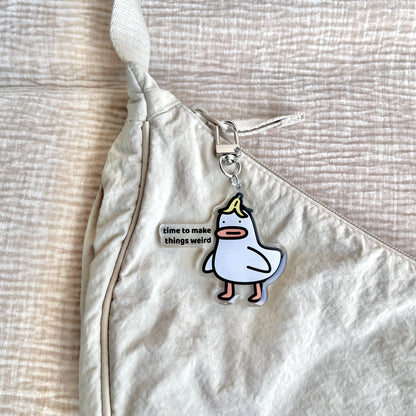 waterproof acrylic goose keychain with the text “Time to make things weird" on a bag