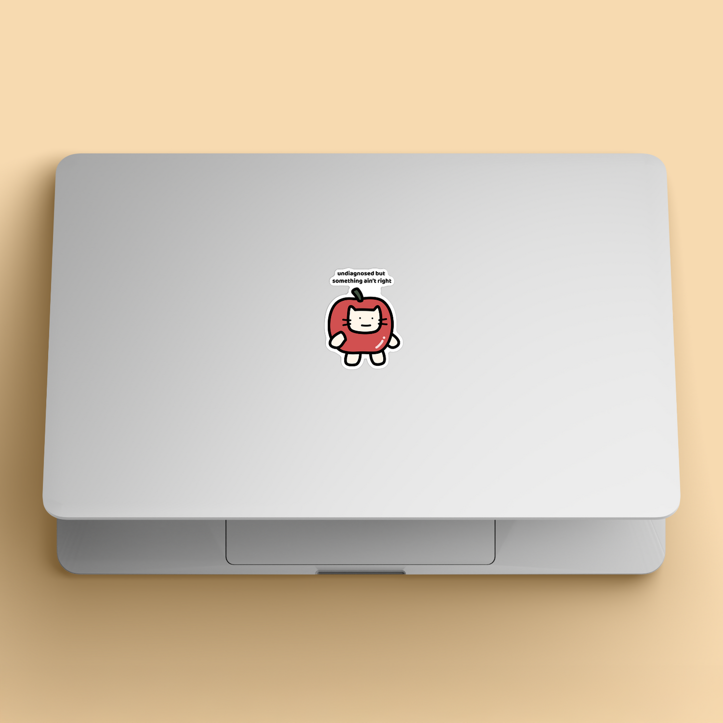 waterproof apple cat vinyl sticker with the text "Undiagnosed but something ain't right" on a laptop