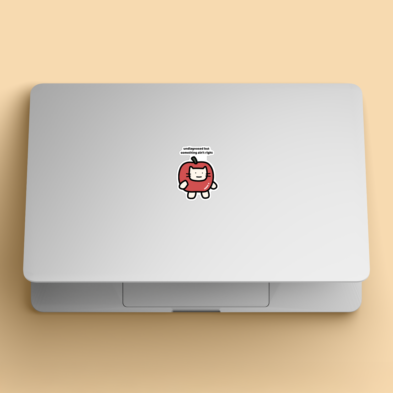 waterproof apple cat vinyl sticker with the text "Undiagnosed but something ain't right" on a laptop
