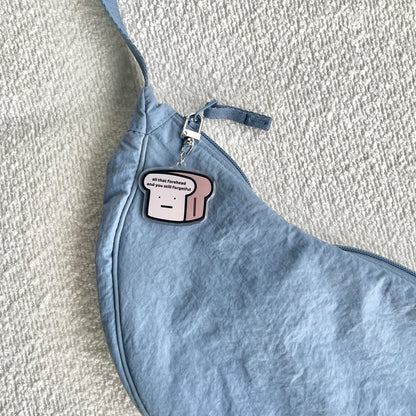 waterproof bread acrylic keychain with the text “All that forehead and you still forgetful" on a bag