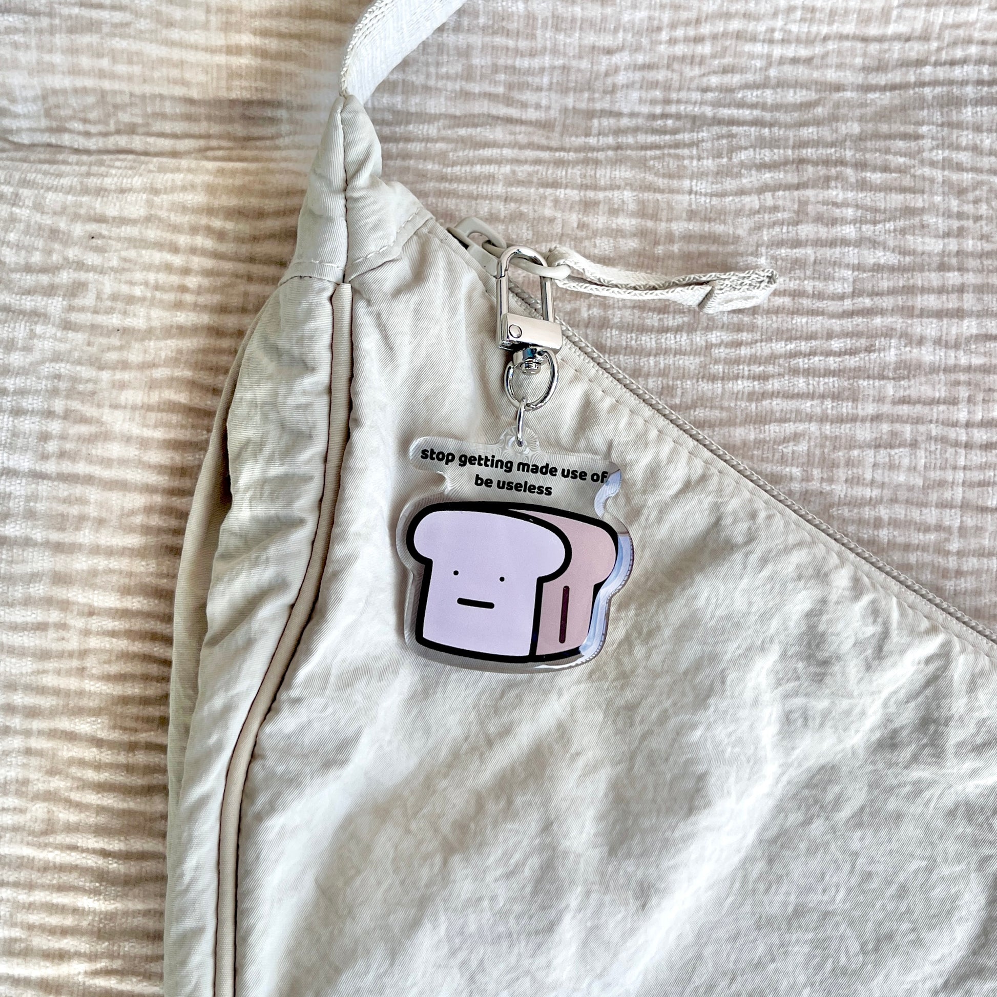 waterproof bread acrylic keychain with the text “Stop getting made use of, be useless" on a bag