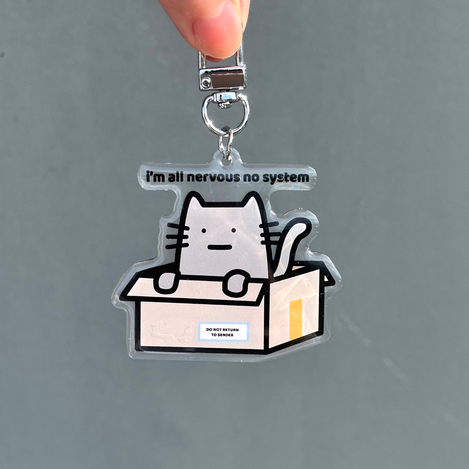 waterproof cat acrylic keychain with the text “I'm all nervous no system" on a plain background