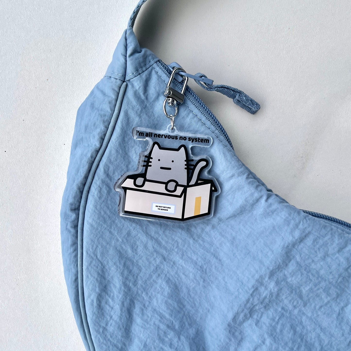 waterproof cat acrylic keychain with the text “I'm all nervous no system" on a bag