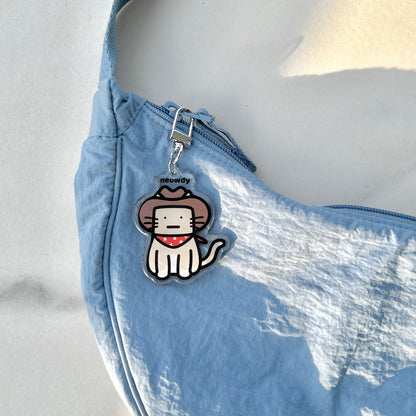 waterproof cat acrylic keychain with the text “Meowdy" on a bag