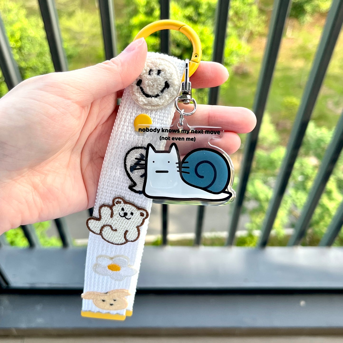 waterproof cat snail acrylic keychain with the text “Nobody knows my next move (Not even me)" on a person's hand