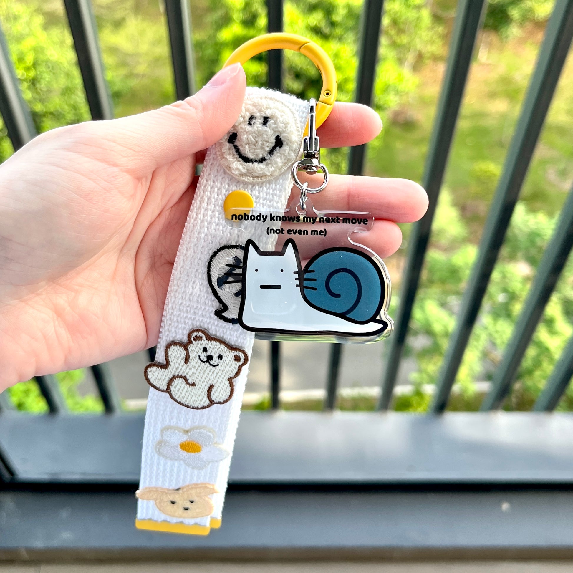 waterproof cat snail acrylic keychain with the text “Nobody knows my next move (Not even me)" on a person's hand