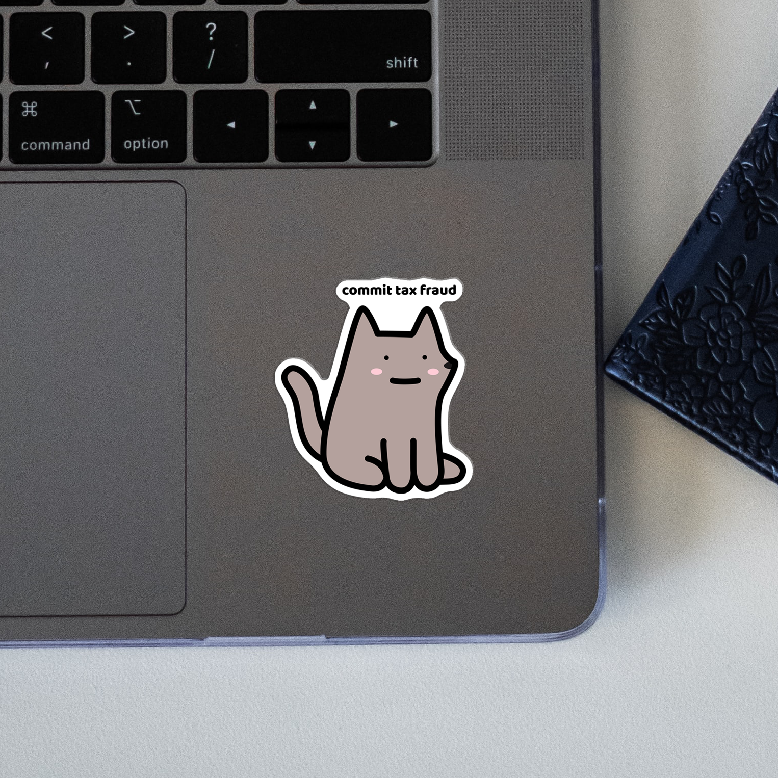 closeup of waterproof dog vinyl sticker with the text "Commit tax fraud"