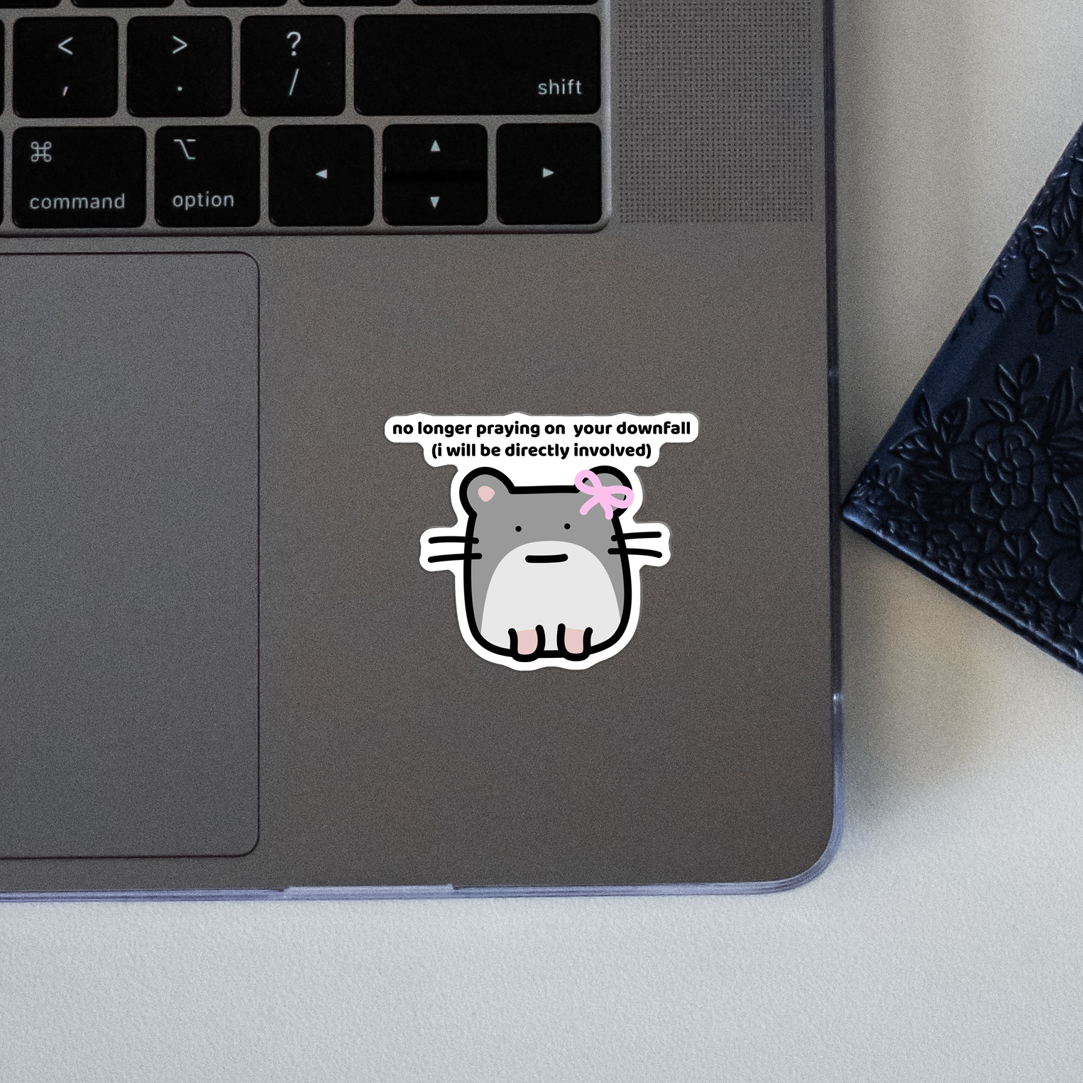 Closeup of waterproof hamster vinyl sticker with the text "No longer praying on your downfall, I will be directly involved"