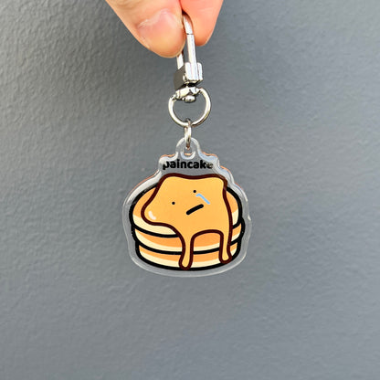 waterproof pancake acrylic keychain with the text “Paincake" on a plain background