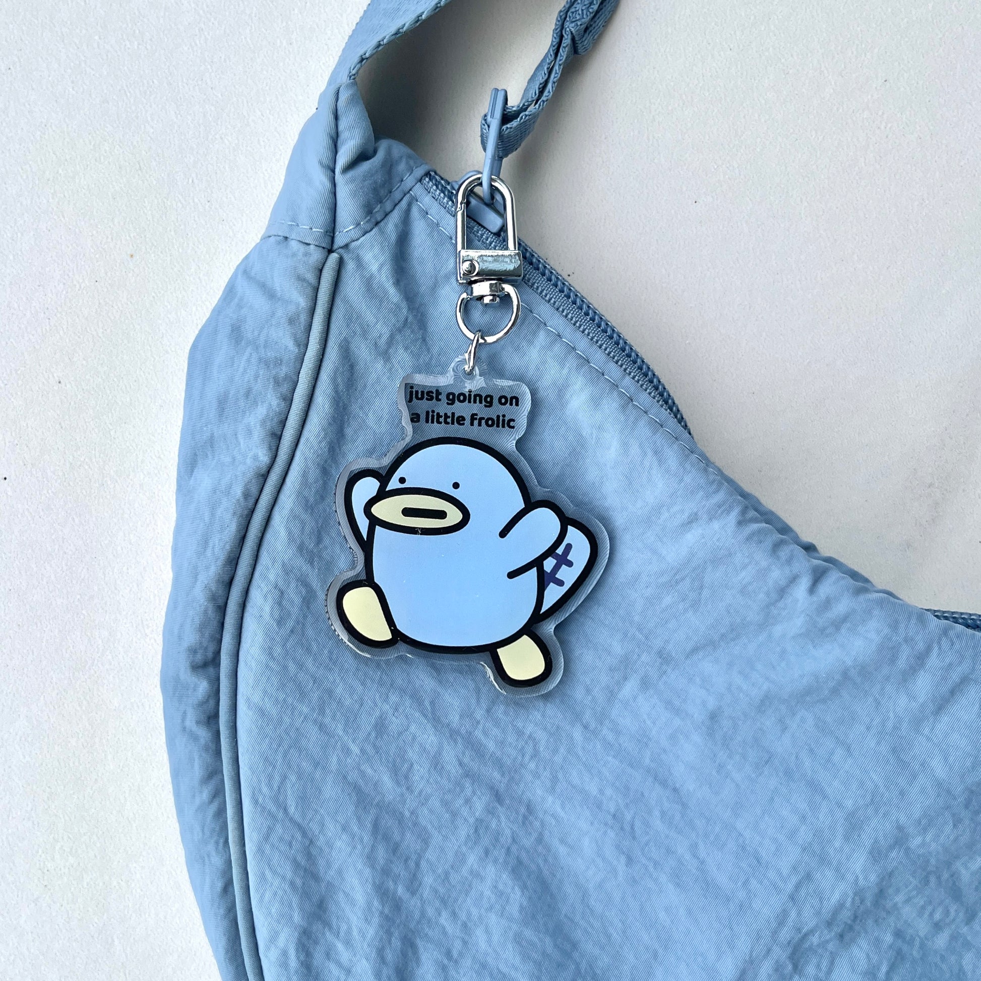 waterproof platypus acrylic keychain with the text “Just going on a little frolic" on a bag