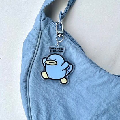 waterproof platypus acrylic keychain with the text “Just going on a little frolic" on a bag