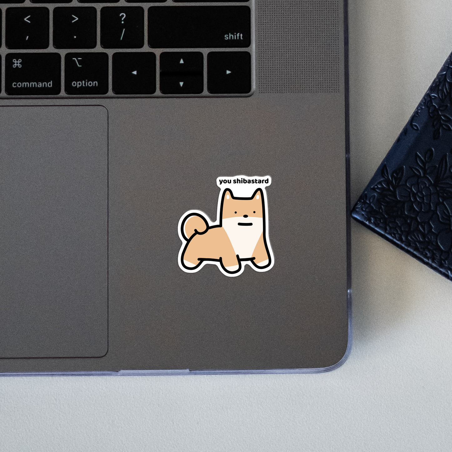 closeup of waterproof shiba vinyl sticker with the text "You shibastard"