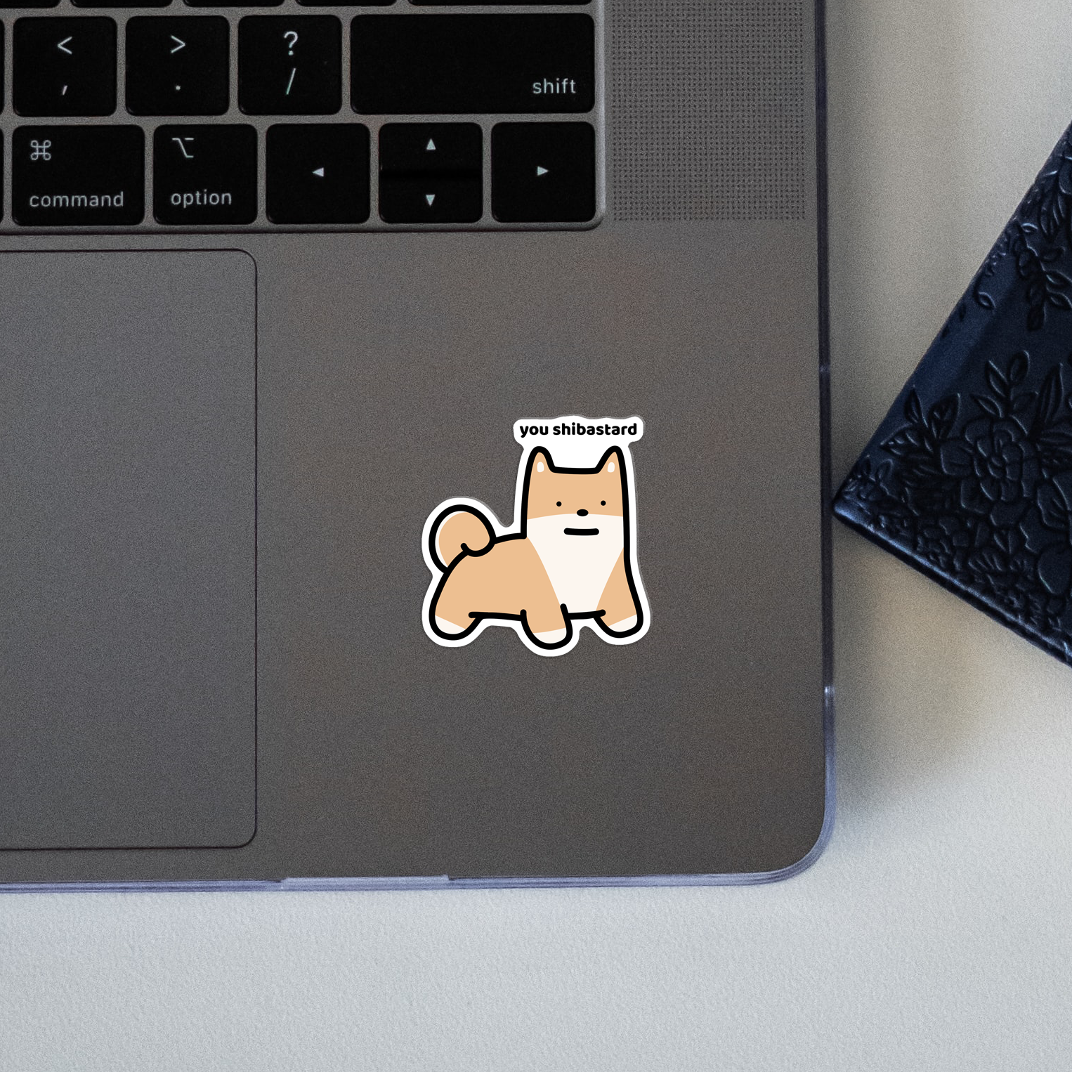 closeup of waterproof shiba vinyl sticker with the text "You shibastard"
